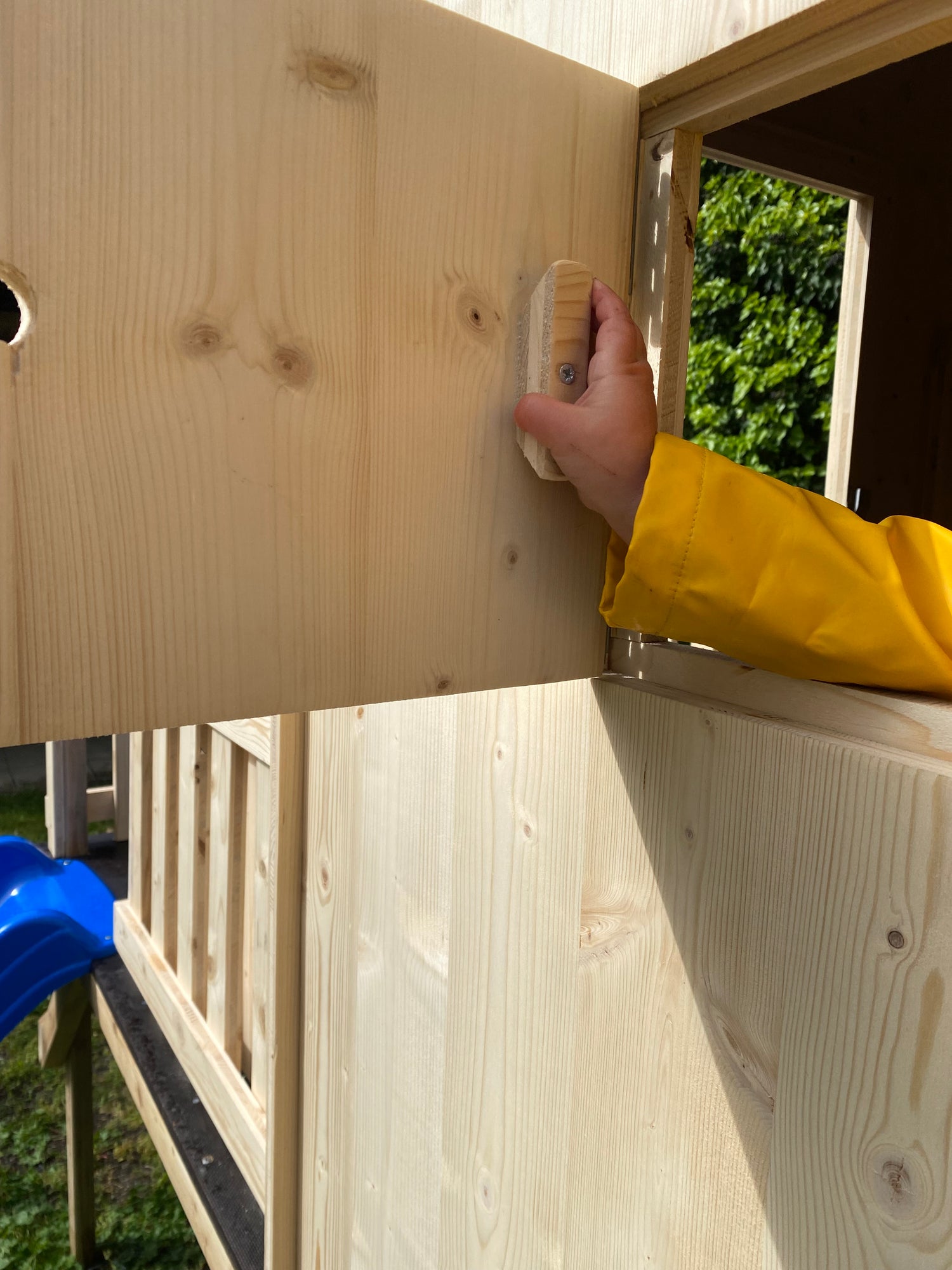 enfant qui ouvre les volets de sa petite cabane en bois